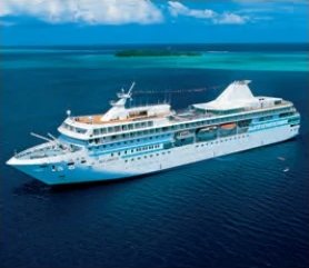 Le bateau de croisière M/S Paul Gauguin vu du ciel sur un lagon bleu.