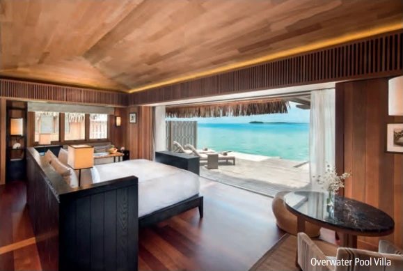 Chambre d’une Overwater Pool Villa avec lit, plafond en bois et terrasse ouverte sur le lagon.
