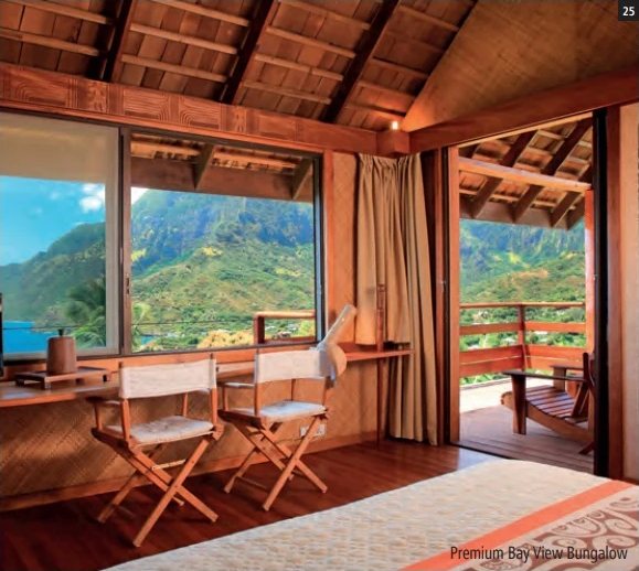 Chambre de bungalow avec chaises de metteur en scène, grandes baies vitrées et terrasse donnant sur les montagnes verdoyantes.