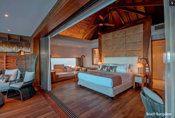 Intérieur d'un Beach Bungalow avec grand lit, plafond en bois et parquet.